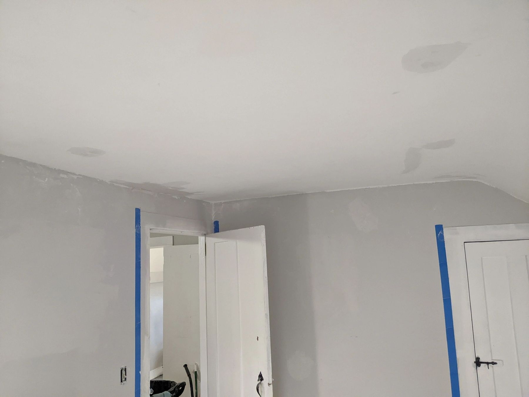 Room with smooth repaired walls and ceiling, door frames taped for painting