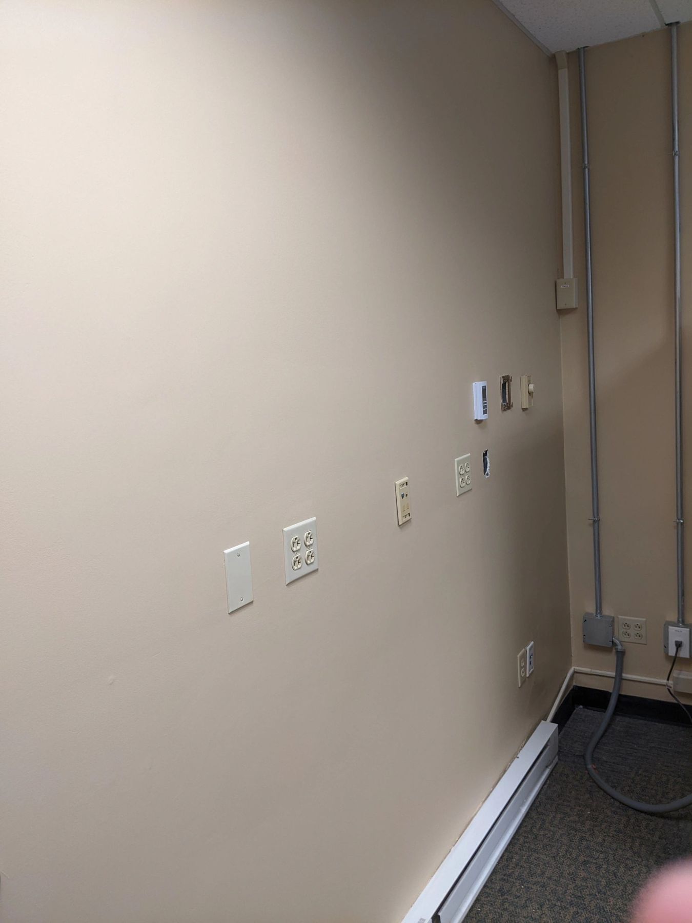 Finished smooth beige wall with outlets and baseboard