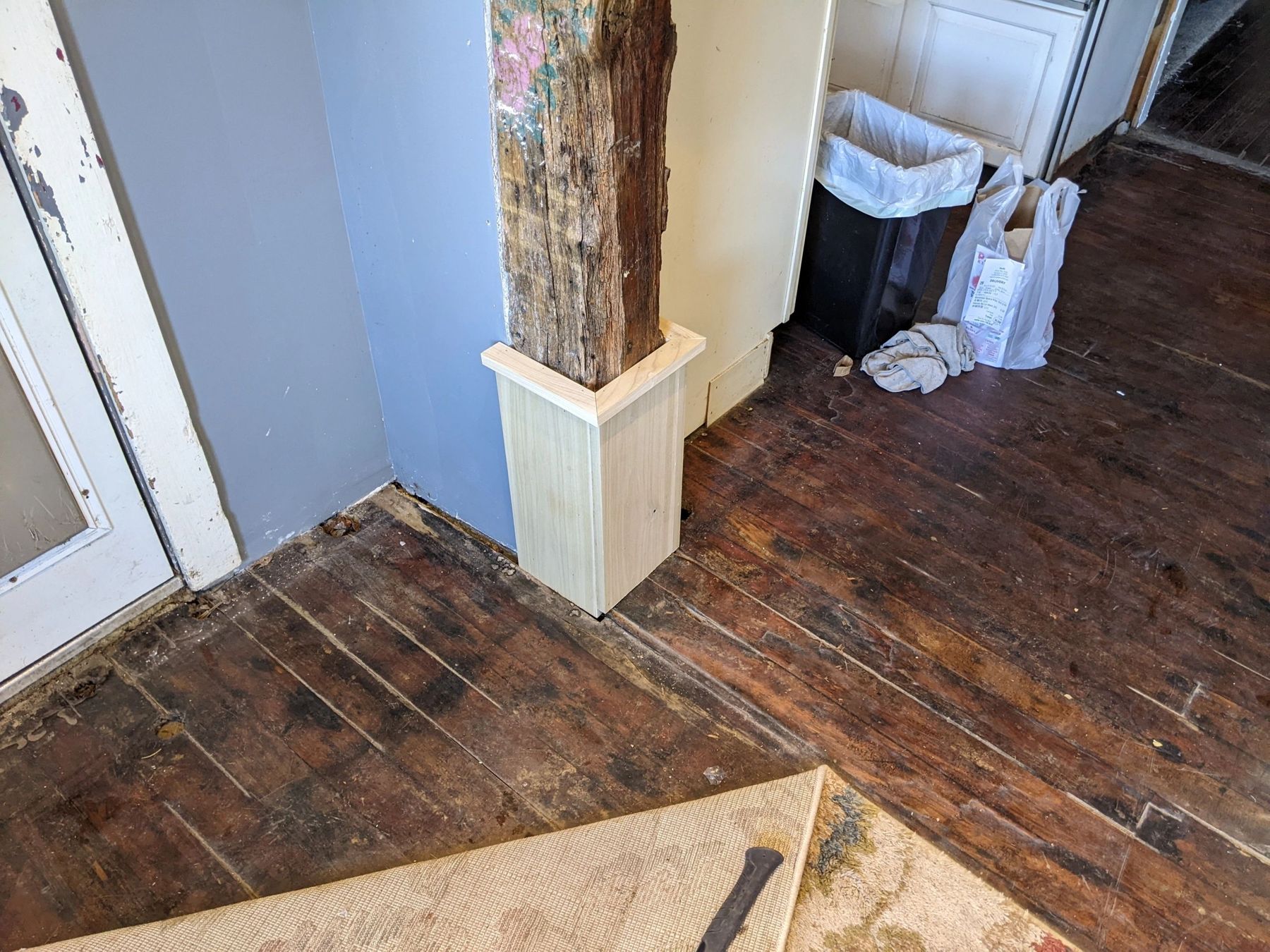 Worn wooden floor boards next to a column during board replacement